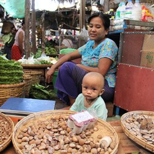 a local woman selling her product while taking care her son