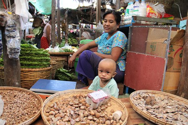 a local woman selling her product while taking care her son